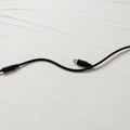 A black USB cable with a braided texture is set on a white surface. The cable features Royalty Free Stock Photo