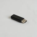 A black USB flash drive rests on a light gray surface. It features a rectangular plastic Royalty Free Stock Photo