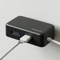 A black USB hub is mounted on a light gray wall. It features multiple ports, including a Royalty Free Stock Photo