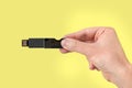 Black USB pen drive on hand with isolated yellow background Royalty Free Stock Photo