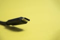 Black usb type C cable on yellow background. Copy space, a place for the text. Selective focus. Communication cable for connecting