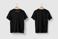 Black V Neck T Shirt mockup on wooden hanger isolated on light grey background front and rear side view. Royalty Free Stock Photo