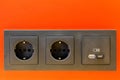 A black 220V, USB and USB C socket block is built into the orange wall surface