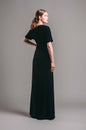 Black velvet trumpet dress. Evening floor length gown with deep v neck line and short sleeves. Beautiful young brunette lady Royalty Free Stock Photo