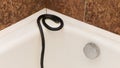 A black venomous snake on edge of white bathtub