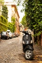 Black Vespa scooter parked on the street in Rome.