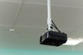 The black video projector is suspended from a long bracket under the ceiling. Royalty Free Stock Photo