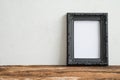 Black vintage photo frame on old wooden table over white wall ba Royalty Free Stock Photo