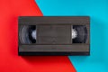 Black vintage VHS videotape cassette on red and blue background. Plastic retro video cassette with analog magnetic tape Royalty Free Stock Photo