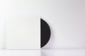 Black vinyl record, in its white box, with blank space to write. With white background. Minimalist photo