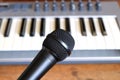 Black vocal microphone closeup against electronic synthesizer keyboard