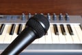 Black vocal microphone closeup against electronic synthesizer keyboard