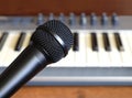 Black vocal microphone closeup against electronic synthesizer keyboard