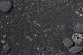 Black volcanic sand background with lava rocks