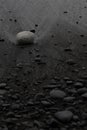 Black volcanic sand on beach with white stone, pebbles, texture, background, vertical. Royalty Free Stock Photo