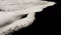 Black volcanic sand and white foam sea wave. Closeup of a natural landscape. Royalty Free Stock Photo