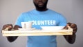 Black volunteer holding serving tray, helping patients in rehabilitation center