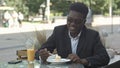 Black waiter serving terrace cafe guests at table Royalty Free Stock Photo