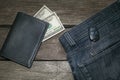 Black wallet, american dolla and key from car in jeans on wooden board.