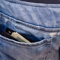 Black wallet with money, sticking out of the back pocket of th