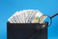 Black wallet with one hundred dollar bills and two hundred euro bil on a blue background. Checks dollar bills with a magnifying Royalty Free Stock Photo
