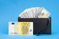 Black wallet with one hundred dollar bills and two hundred euro bill on a blue background Royalty Free Stock Photo