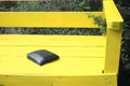Black wallet resting on a bright yellow bench outdoors Royalty Free Stock Photo