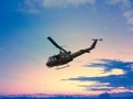 Black helicopter flying in nice sunset with red and yellow blue sky on mountain and tree wood