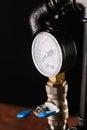 Black water pipes with red taps and a gauge pressure meter Royalty Free Stock Photo