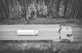 Black and white abstract image of white truck of logisctic company with cargo and its big silhouette is driving on th Royalty Free Stock Photo