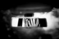 Black and white art picture of young woman with frightened eyes covering her face with hands in the car rear view mirror. Royalty Free Stock Photo