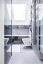 Black and white bathroom interior with reflective tiles, a ceramic toilet and bright light coming through a roof window Royalty Free Stock Photo