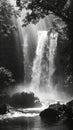 A black and white capture of a powerful waterfall, with rays of light creating a dramatic contrast against the dark Royalty Free Stock Photo
