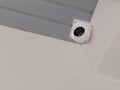 Black and white CCTV camera mounted on a grey roof and white wall background, object, technology, care, decor, copy space Royalty Free Stock Photo