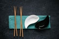 Black and white ceramic bowls and chopsticks lying on linen napkin, dark background, top view Royalty Free Stock Photo