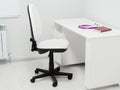 Black white chair and table with purple stethoscope and red medical journal in doctors office. Workplace Royalty Free Stock Photo