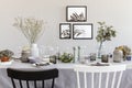 Black and white chair at table with tableware in grey dining room interior with posters Royalty Free Stock Photo