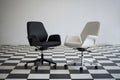 Black and white chairs on checkered floor, emphasizing modern office style Royalty Free Stock Photo