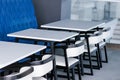 Black and white chairs and tables on the food court against a blue wall. Cafe interior. Royalty Free Stock Photo