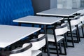 Black and white chairs and tables on the food court against a blue wall. Cafe interior. Royalty Free Stock Photo