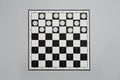 Black and white checkerboard with game pieces on light grey background, top view Royalty Free Stock Photo