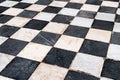 Black and white checkerboard tiles, old with scratches and scuffs.