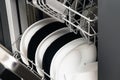 Black and white clean plates in the dishwasher, background close-up Royalty Free Stock Photo