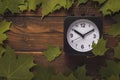 Black and white clock in a frame of maple leaves on a deervyannom background Royalty Free Stock Photo