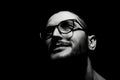 Black and white, close-up dark portrait of young smiling man wearing glasses. Royalty Free Stock Photo