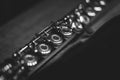 A black and white close up portrait of a the valves of an assembled silver metal flute. The musical instrument is ready to be