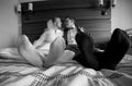 Black and white closeup of bride and groom's feet lying on bed