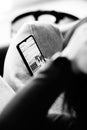 Black and white closeup shot of woman sitting on couch and looking at smartphone