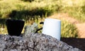 A black and white Cup with a hot drink stands on a large stone in nature. Good morning. Good evening