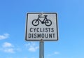 Black and white Cyclists Dismount sign in a blue sky